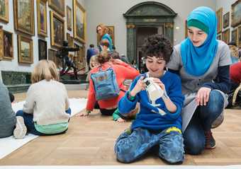 Children and parents sitting on the floor doing an activity in an art gallery