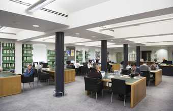 A library space with people sitting and studying at large desks